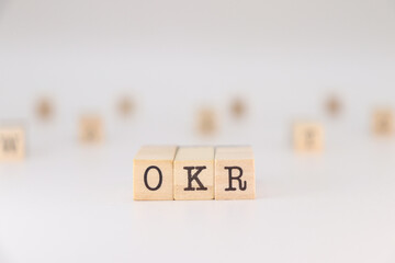 OKR acronym, Concept of Objectives, Key and Results written on wooden cubes isolated on white...