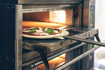 Close-up of a hand placing an uncooked pizza