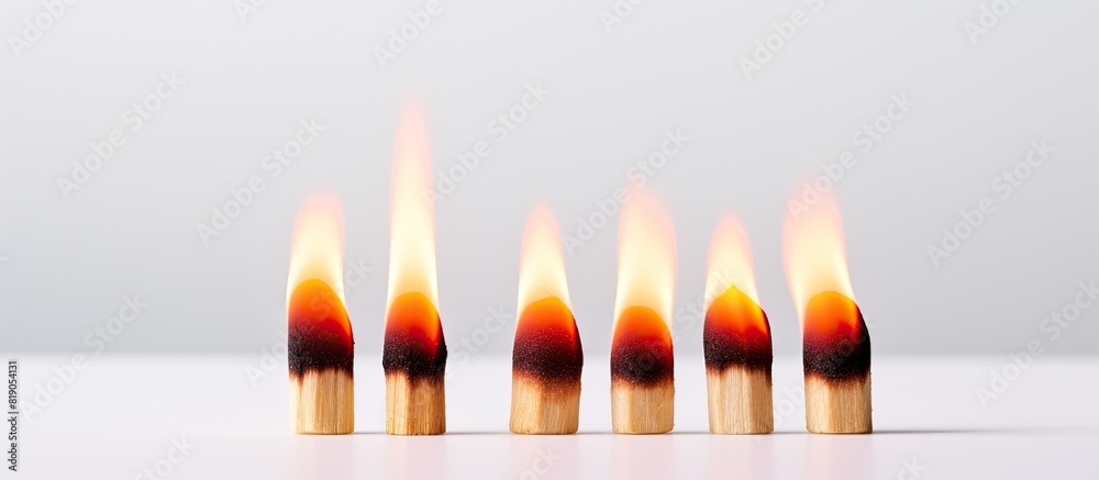 Poster A copy space image of a row of three matches one of which is lit burning on a white background