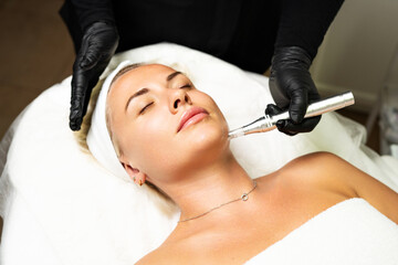 Microneedle RF lifting procedure. A cosmetologist performs a facial rejuvenation procedure on a woman. Hardware cosmetology.