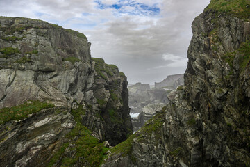 A View of Rocky Cliff With Body of Water in Distance