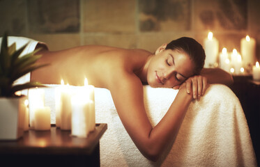 Woman, relax and massage bed in salon for glow, wellness and cosmetics with candles. Zen, beauty...