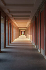 The hallway is long with red walls and columns, creating a bold aesthetic