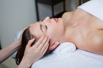 Beautiful young woman getting facial massage in spa salon. Beauty treatment concept.