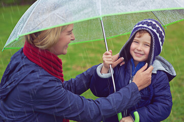 Mother, boy and rain for umbrella, smile and child with portrait for winter and safety of...