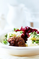 Hamburger steak with potatoes and fresh herbs on bright background. Close up.	