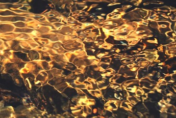 Gold flowing pattern, The clear golden surface of the water sways with the flow of the water in the stream.