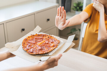 Diet concept, unhappy asian young woman, girl refusing to eat Pizza in box at home, hand pushing...
