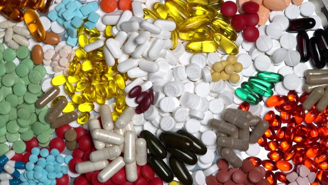 Pills and medication capsules rotation on the plate. Various prescription meds, liquid vitamins, painkillers, antidepressants and sleep meds, vitamins and anti inflammatory, blood pressure tablets.