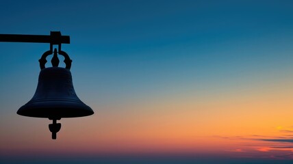 Large bell silhouetted against vibrant sunset sky