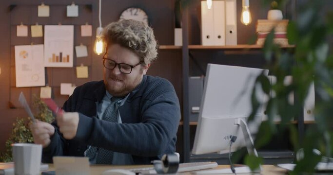 Loop of crazy businessman listening to music and playing imaginary drums with pencils having fun at work in office in evening. Creative people and workplace joy concept.