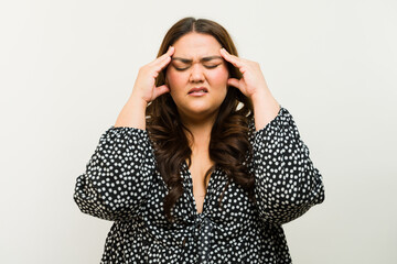 Stressed plus-size woman holds her head, showing signs of a headache or migraine
