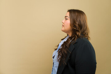 Empowered plus-size woman in formal attire posing from a side view in a studio