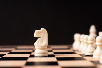 Knight white pawn chess in front of row of chess set black background