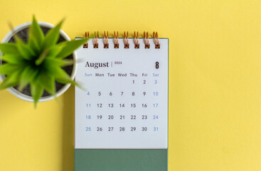 Desktop calendar for August 2024. Monthly planning calendar and vase with dried flowers on the...