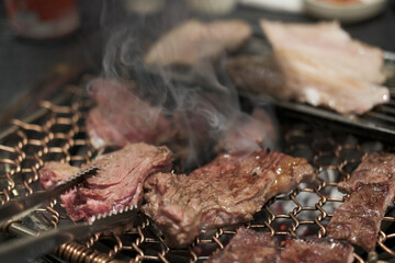 Korean Style Barbecue on stainless grill. BBQ rare meat with soft focus