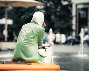 junge frau mit kopftuch wartet am Springbrunnen