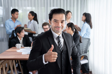 Portrait of happy businessman looking at camera, make approval hand gesture thumb up with motion...