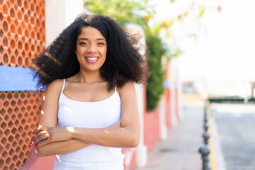 Young African American woman at outdoors keeping the arms crossed in frontal position