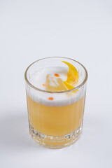 Whisky sour cocktail with foam and ice cube decorated dry orange peel