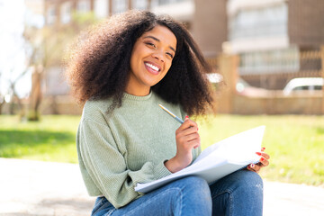 Young African American woman at outdoors holding a notebook