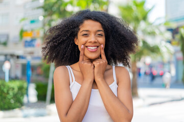 Young African American woman at outdoors smiling with a happy and pleasant expression