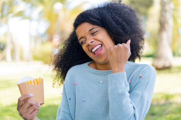 Young African American woman holding fried chips at outdoors celebrating a victory