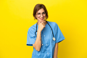 Surgeon doctor woman isolated on yellow background with glasses and smiling