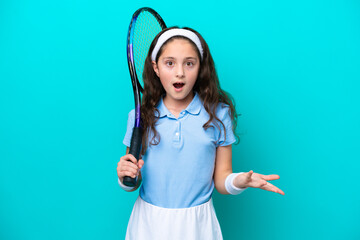 Little caucasian girl playing tennis isolated on blue background with shocked facial expression