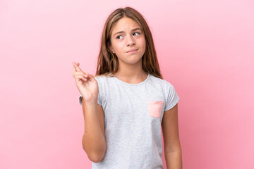Little caucasian girl isolated on pink background with fingers crossing and wishing the best