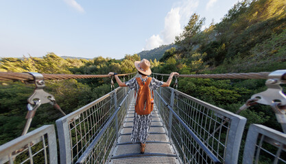 girl in a hat walks along a suspension bridge. Autumn season outdoors, portrait of a woman walking...