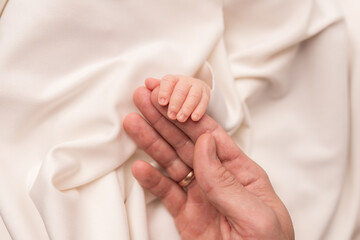 Handle of a newborn baby in parental hands.	