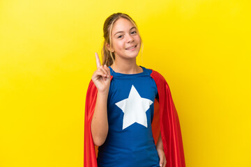 Super Hero little girl isolated on yellow background showing and lifting a finger in sign of the...