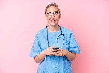 Young surgeon nurse woman isolated on pink background surprised and sending a message