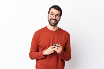 Caucasian handsome man with beard over isolated white background sending a message with the mobile