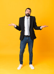 Full-length shot of business man over isolated yellow background having doubts while raising hands