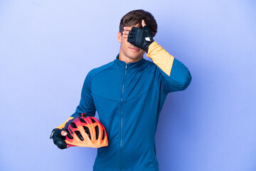 Young cyclist caucasian man isolated on purple background covering eyes by hands. Do not want to...