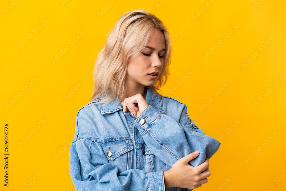 Wall mural young russian woman isolated on yellow background with pain in elbow