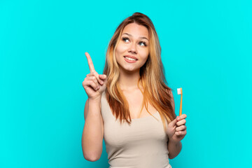 Teenager girl brushing teeth over isolated blue background pointing up a great idea