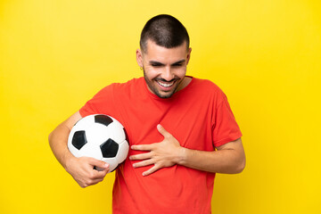 Young caucasian man playing soccer isolated on yellow background smiling a lot