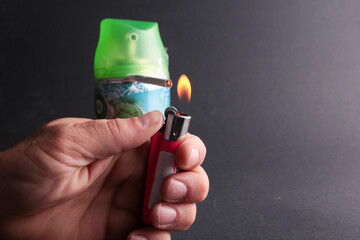 A hand holds a lighter next to a gas can