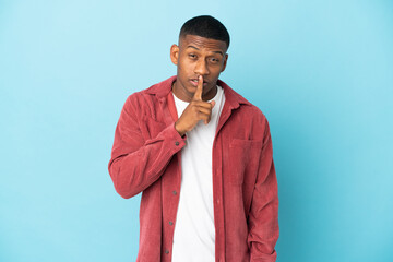 Young latin man isolated on blue background showing a sign of silence gesture putting finger in mouth