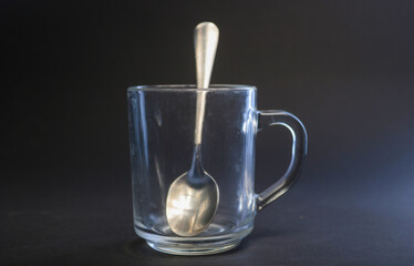 transparent mug with a teaspoon on a black background