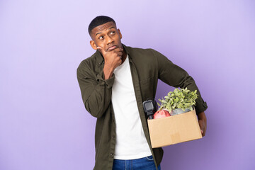 Latin man making a move while picking up a box full of things having doubts