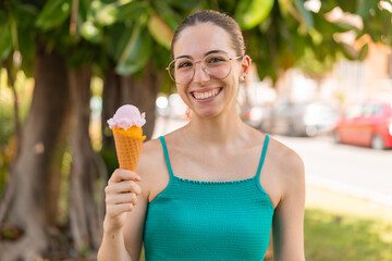 Young pretty woman with a cornet ice cream at outdoors smiling a lot