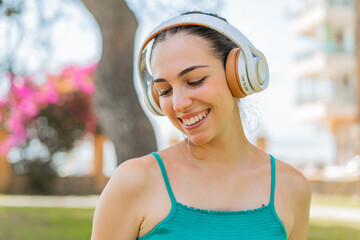 Young pretty woman at outdoors listening music