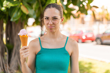 Young pretty woman with a cornet ice cream at outdoors with sad expression