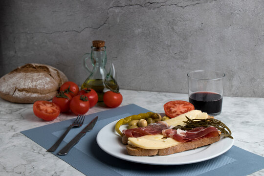 Icon of Mallorcan gastronomy: "pa amb oli". In this case with cheese and ham, on a white marble table.