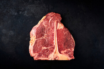Raw dry aged chianina porterhouse beef steak offered as top view on a black board