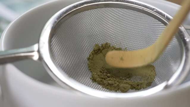 Close up and Slow Motion Footage of Small Spoon Sifting Matcha Powder through Fine Tea Sieve. Green Tea Ceremony 